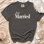 Dark grey t-shirt with "Just Married" text, styled with pearls, a rose, and champagne.