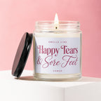 A lit candle in a glass jar, reading "Smells Like Happy Tears & Sore Feet".