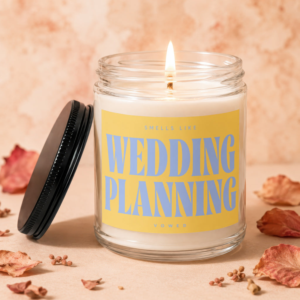 Jar candle with lit wick and yellow label reading "Smells Like Wedding Planning".