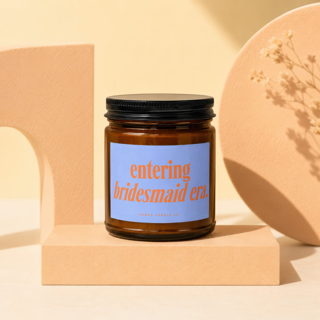 Amber jar candle with a blue label reading "entering bridesmaid era."