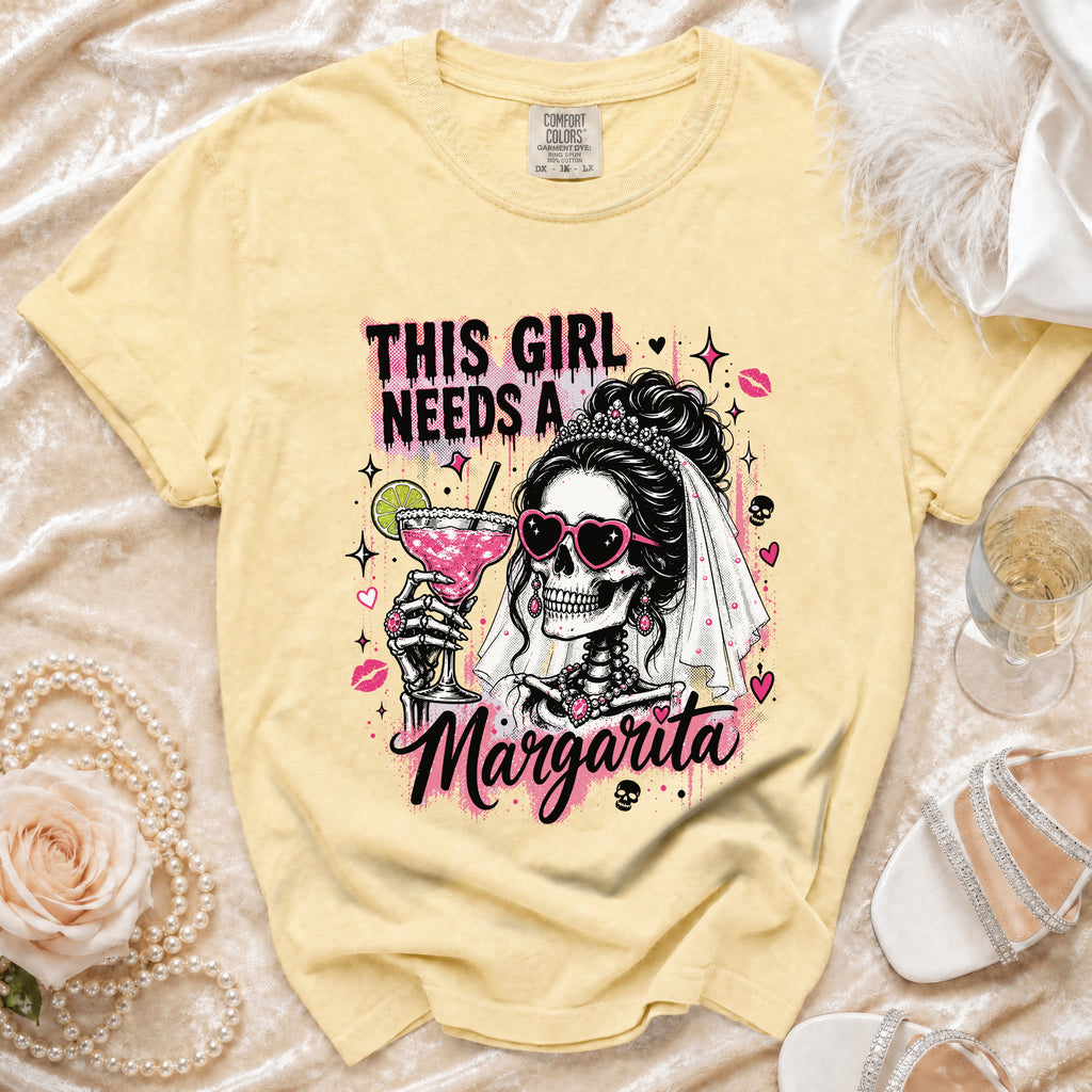 Pale yellow t-shirt graphic of a skeleton bride with "This Girl Needs A Margarita" text.
