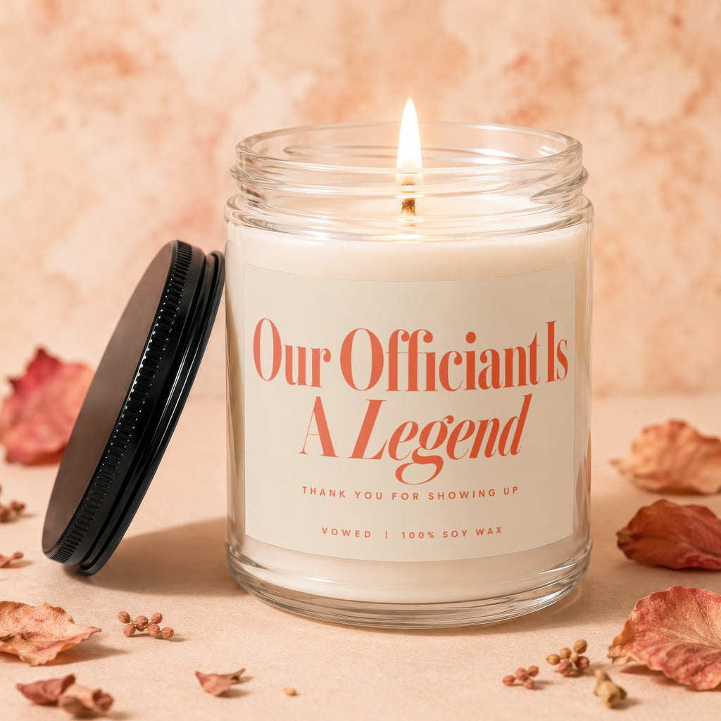 Soy candle with lit flame in glass jar, text "Our Officiant Is A Legend".
