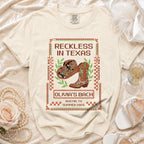 T-shirt with "Reckless in Texas" text, cowboy hat, and boots for Olivia's Bach, Austin, TX.