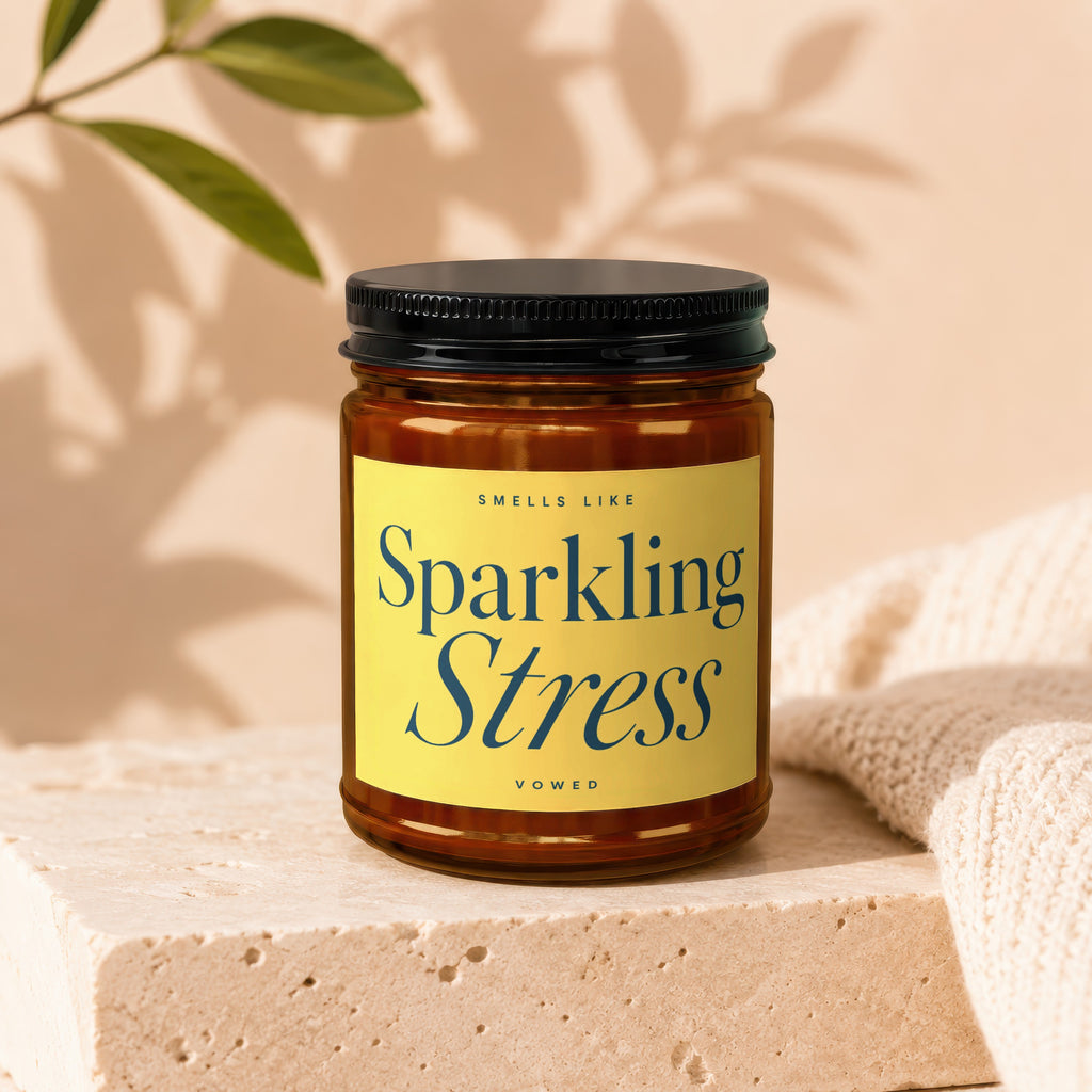 Brown glass candle with yellow label that reads "Sparkling Stress".