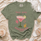 Green t-shirt with "This Girl Needs A Margarita" graphic and cocktail.