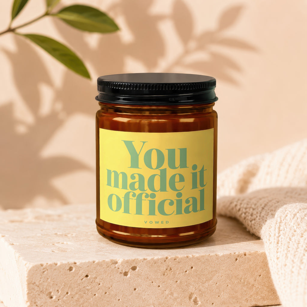 Glass jar candle with a yellow label that reads "You made it official vowed."