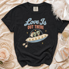 Black t-shirt with "Love Is Out There" text and aliens in a UFO graphic.