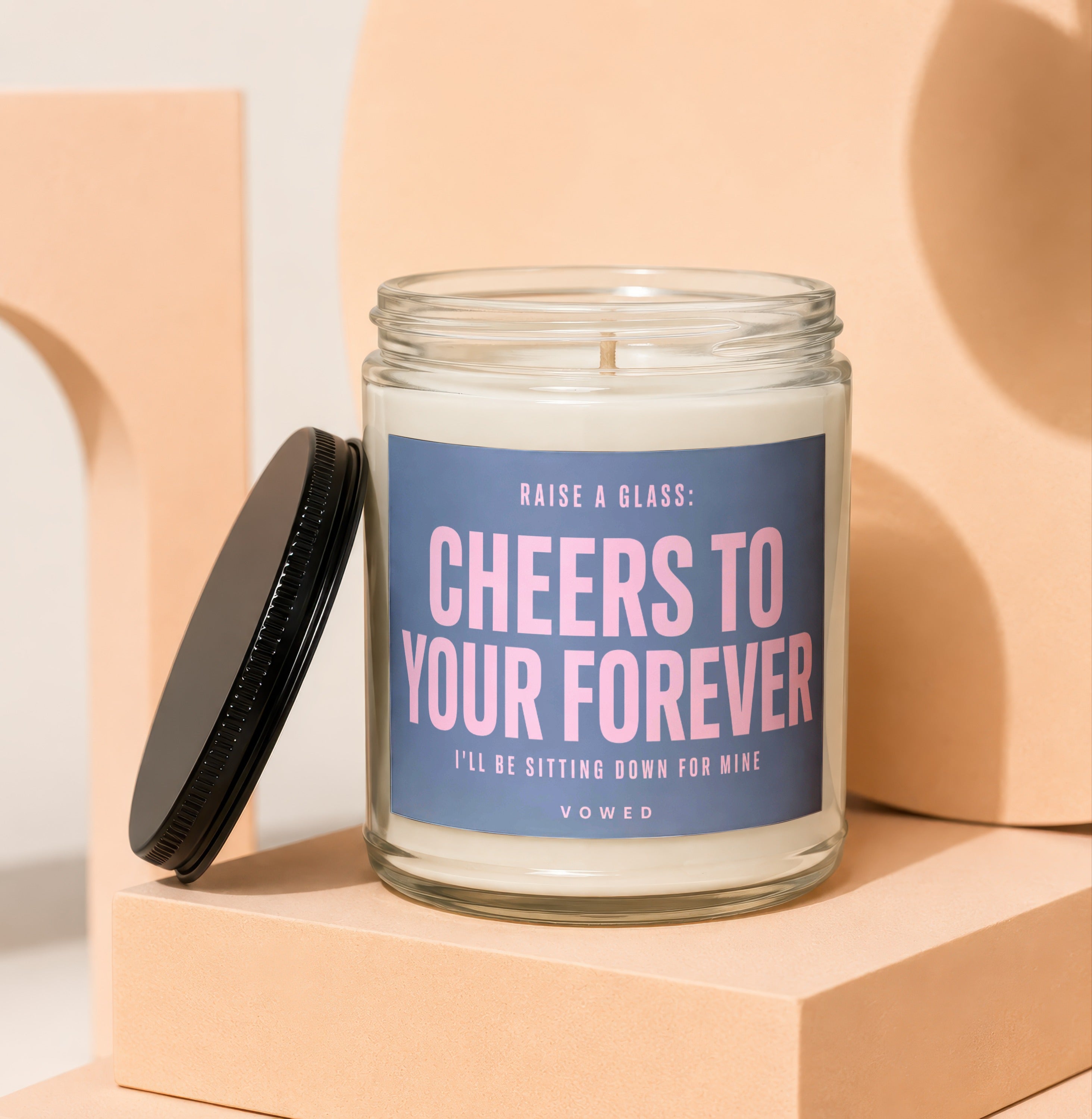Candle with blue label reading "Cheers to Your Forever" and "Vowed."