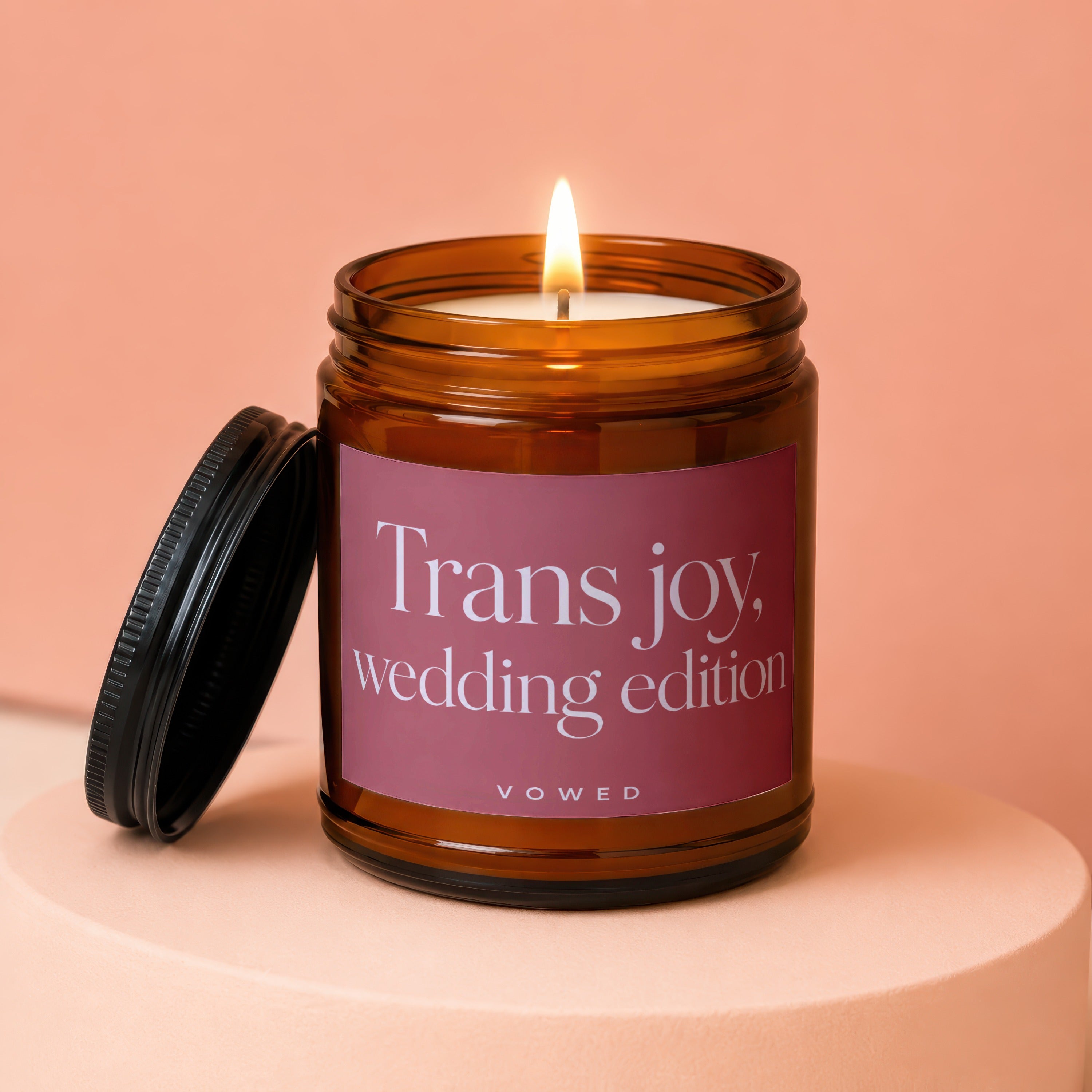 Trans joy wedding edition candle with a lit wick in a brown jar