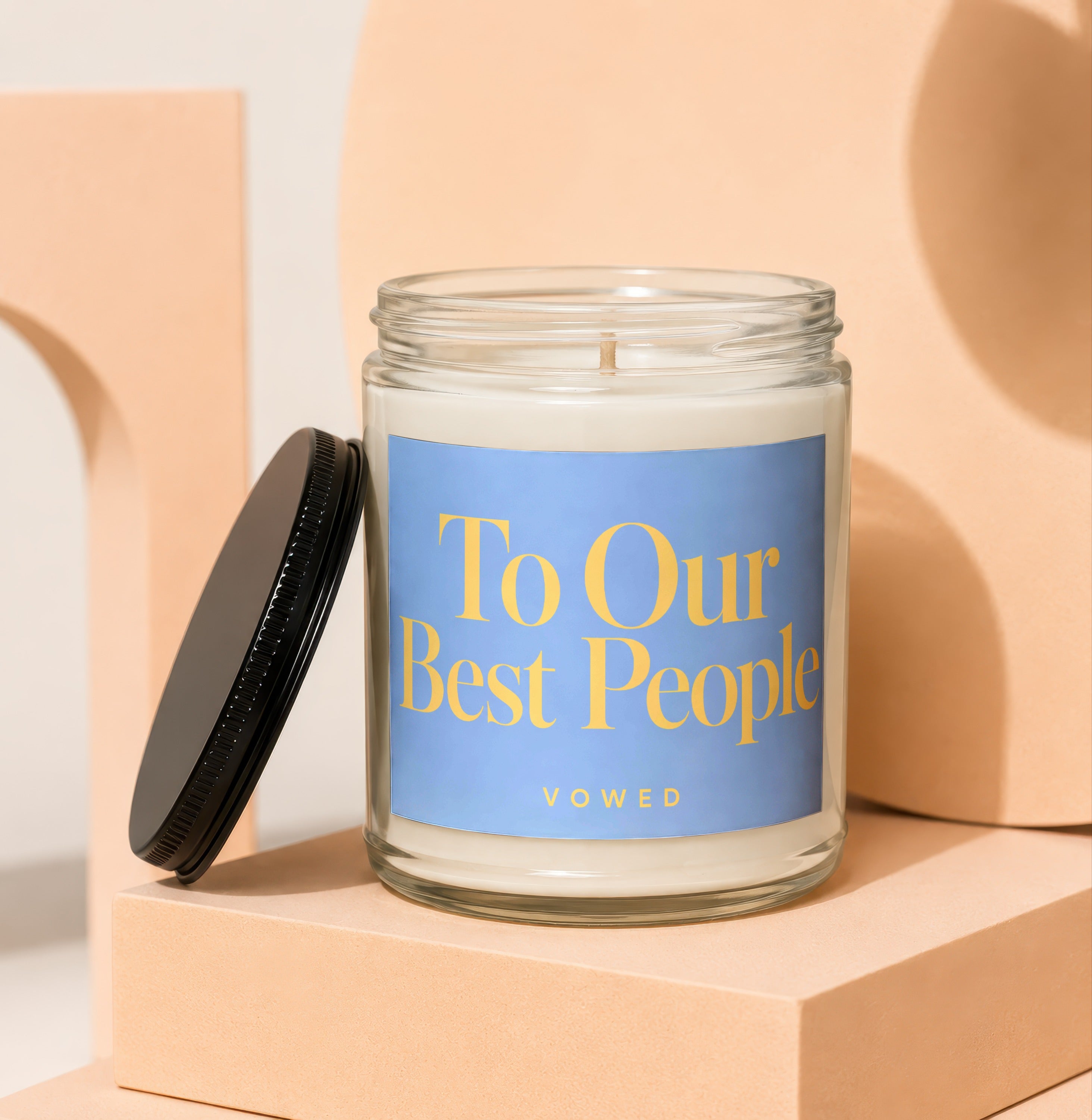 Glass candle with blue label that says "To Our Best People" and "VOWED."
