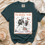 Dark green graphic t-shirt featuring a postage stamp design of a skeleton couple dancing with the text "TIL DEATH".