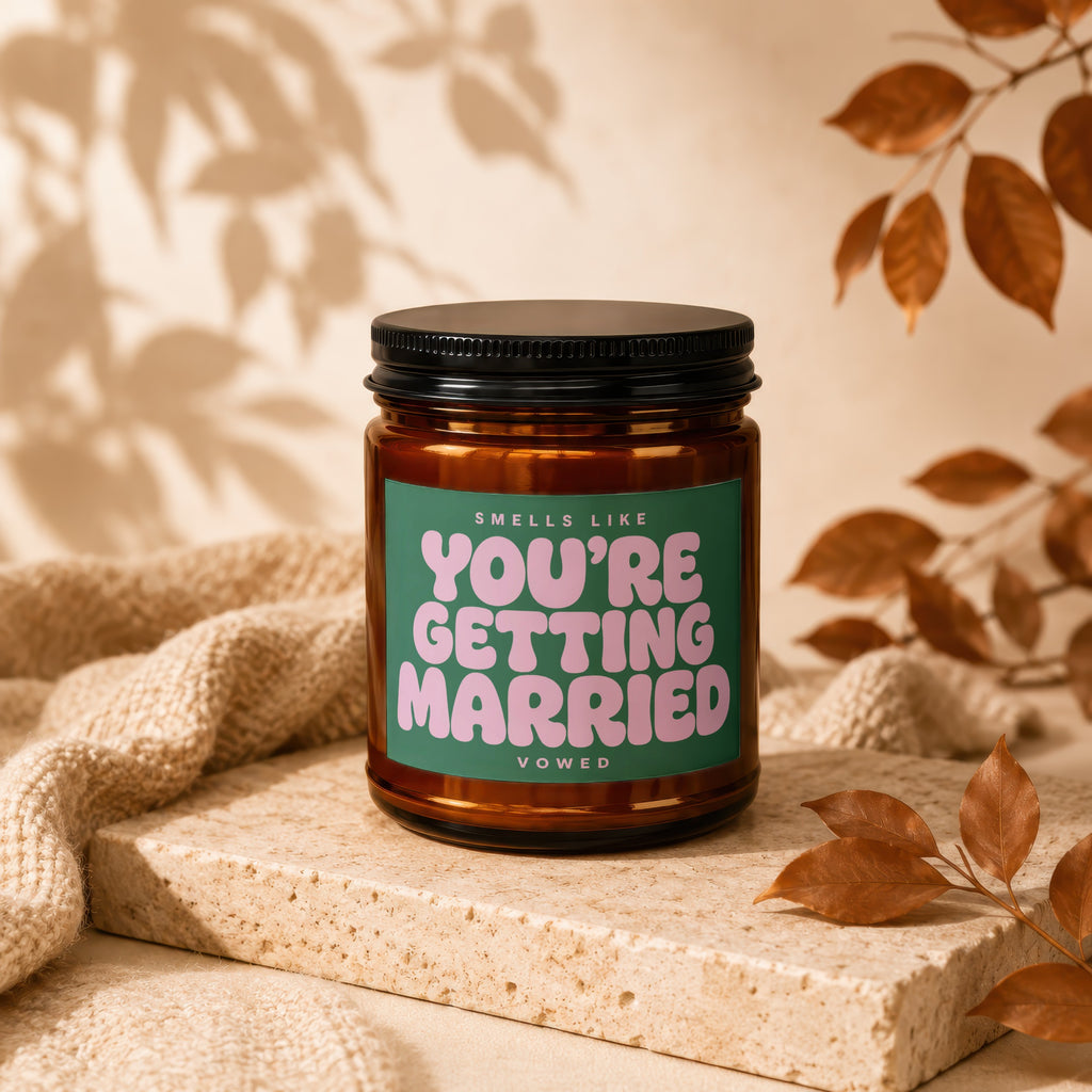 Amber candle with green label that says "SMELLS LIKE YOU'RE GETTING MARRIED VOWED".