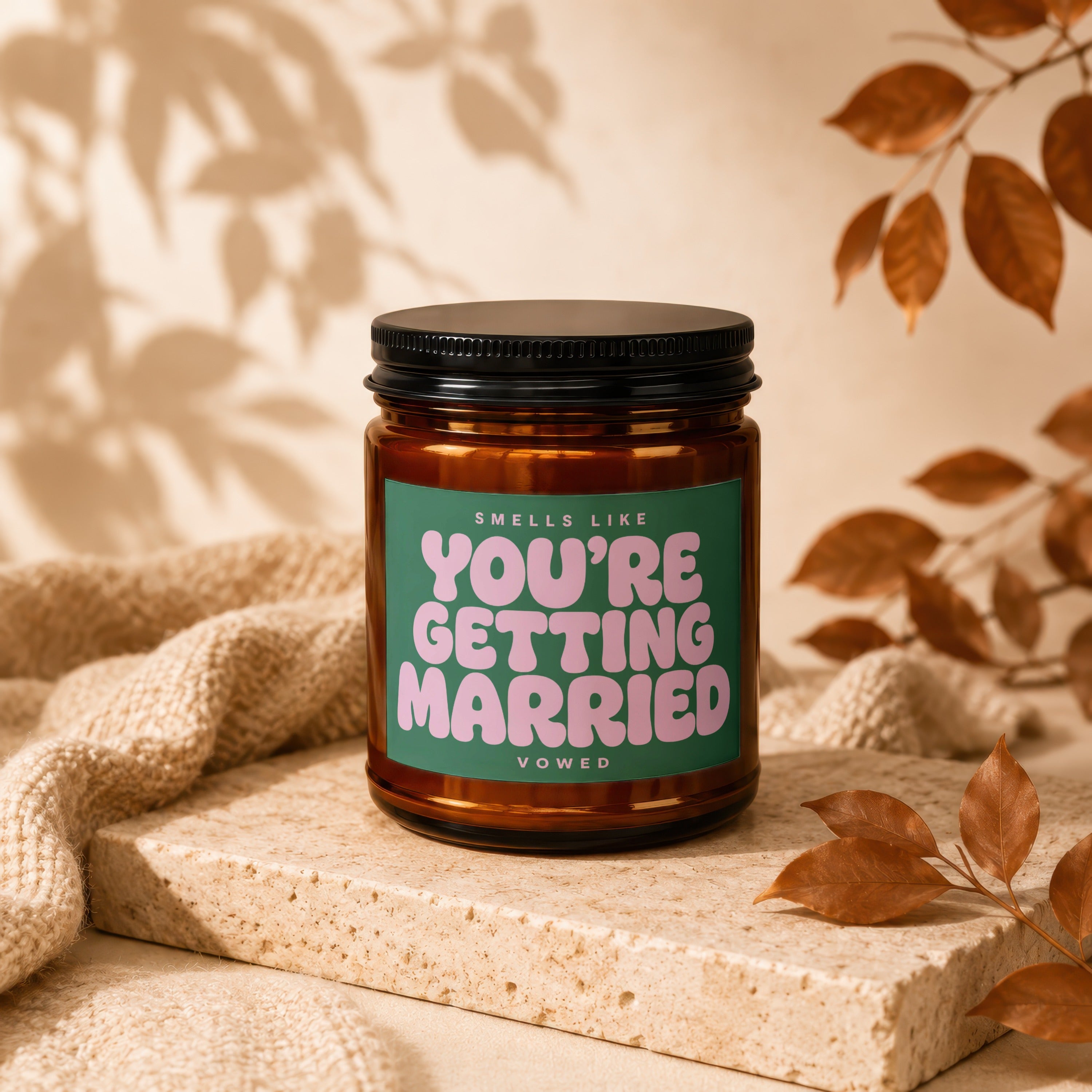 Amber candle with green label that says "SMELLS LIKE YOU'RE GETTING MARRIED VOWED".