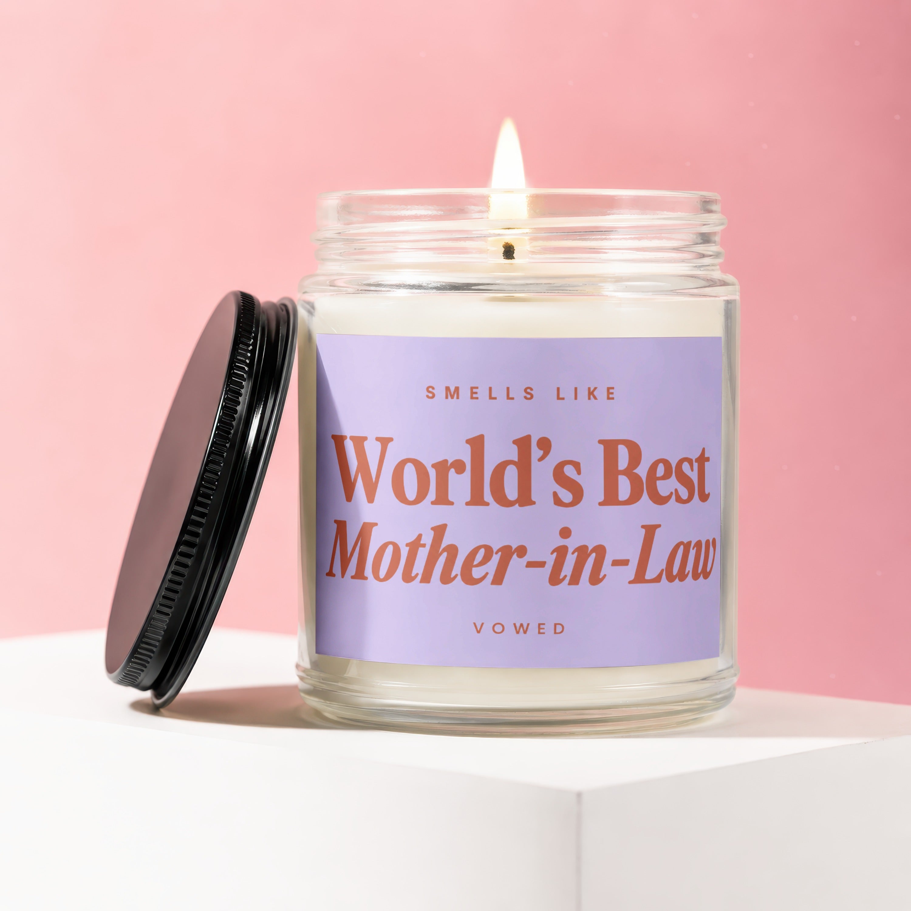Candle with lit wick and label reading "Smells like World's Best Mother-in-Law".