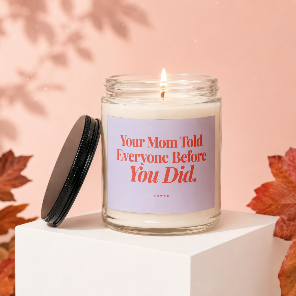Glass jar candle with lid off, lit wick, and text "Your Mom Told Everyone Before You Did."