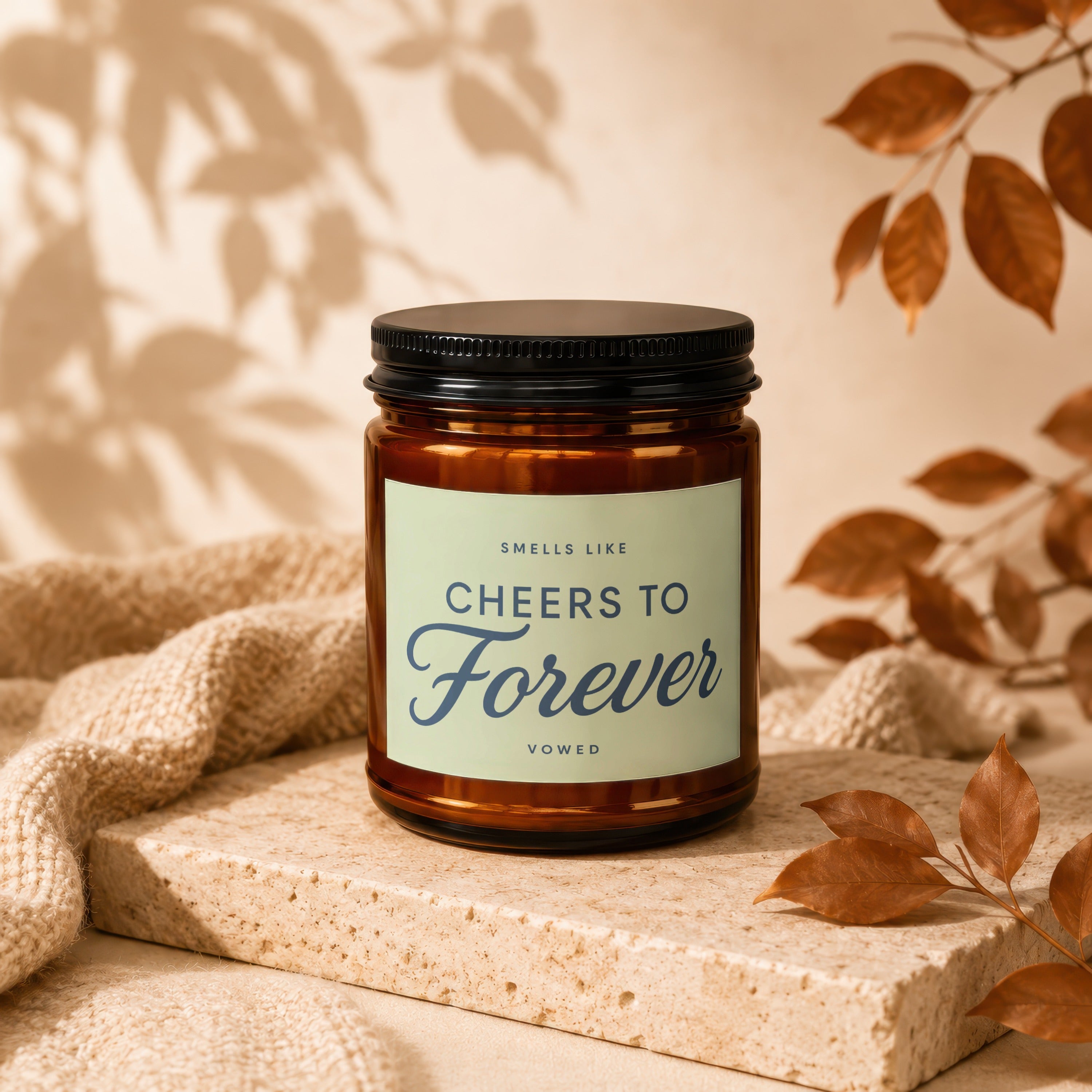 Amber candle with black lid labeled "Smells Like Cheers To Forever Vowed".