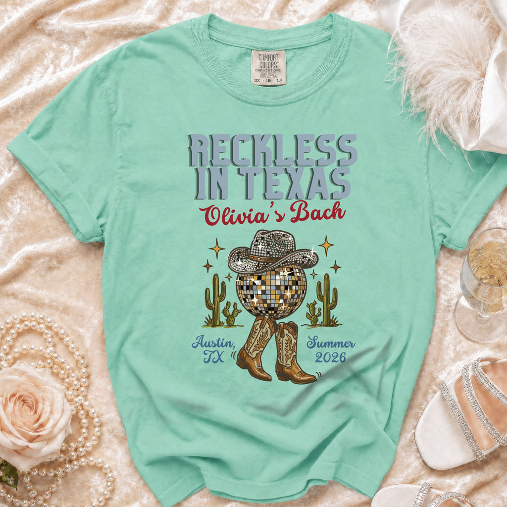Mint green t-shirt with "Reckless in Texas Olivia's Bach" text, disco ball, cactus, and boots.