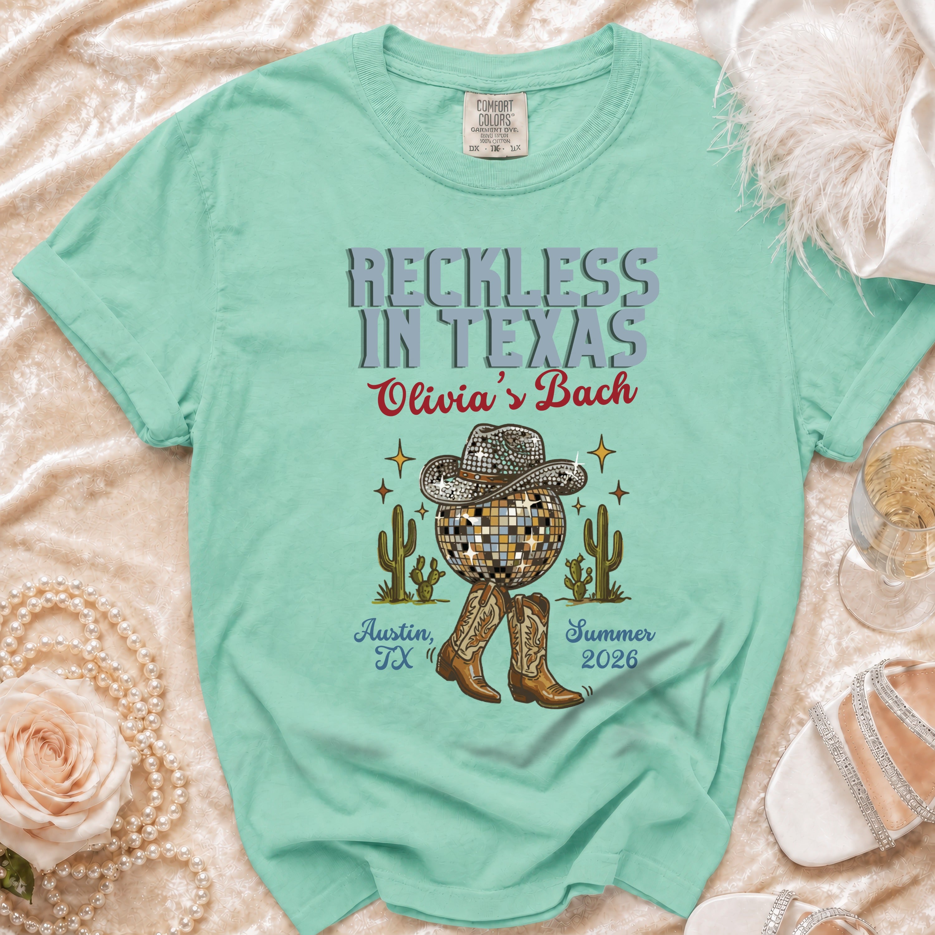 Mint green t-shirt with "Reckless in Texas Olivia's Bach" text, disco ball, cactus, and boots.