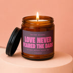 Candle with text "Love Never Feared the Dark" and "vowed" on a pink background.