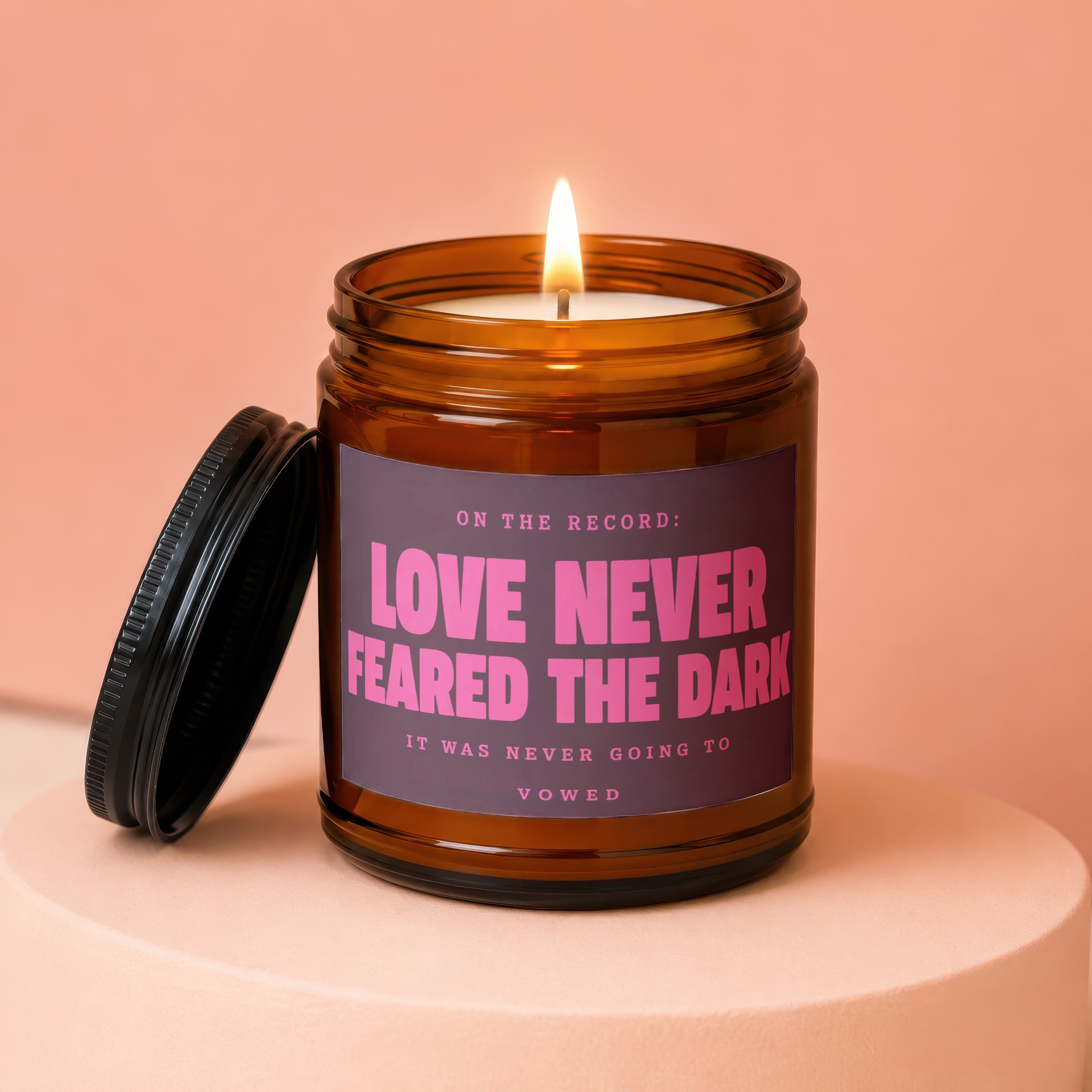 Candle with text "Love Never Feared the Dark" and "vowed" on a pink background.