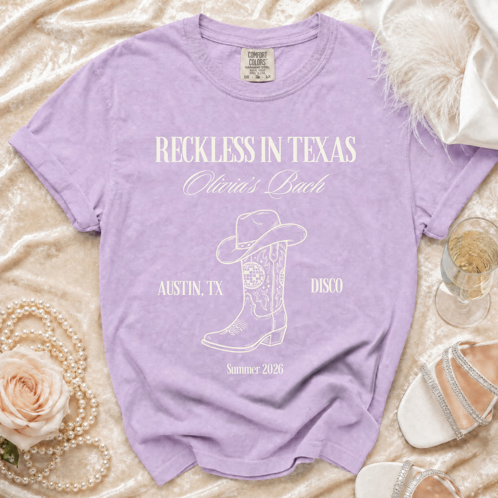 Purple t-shirt with "Reckless in Texas Olivia's Bach" text, disco ball, and boot.