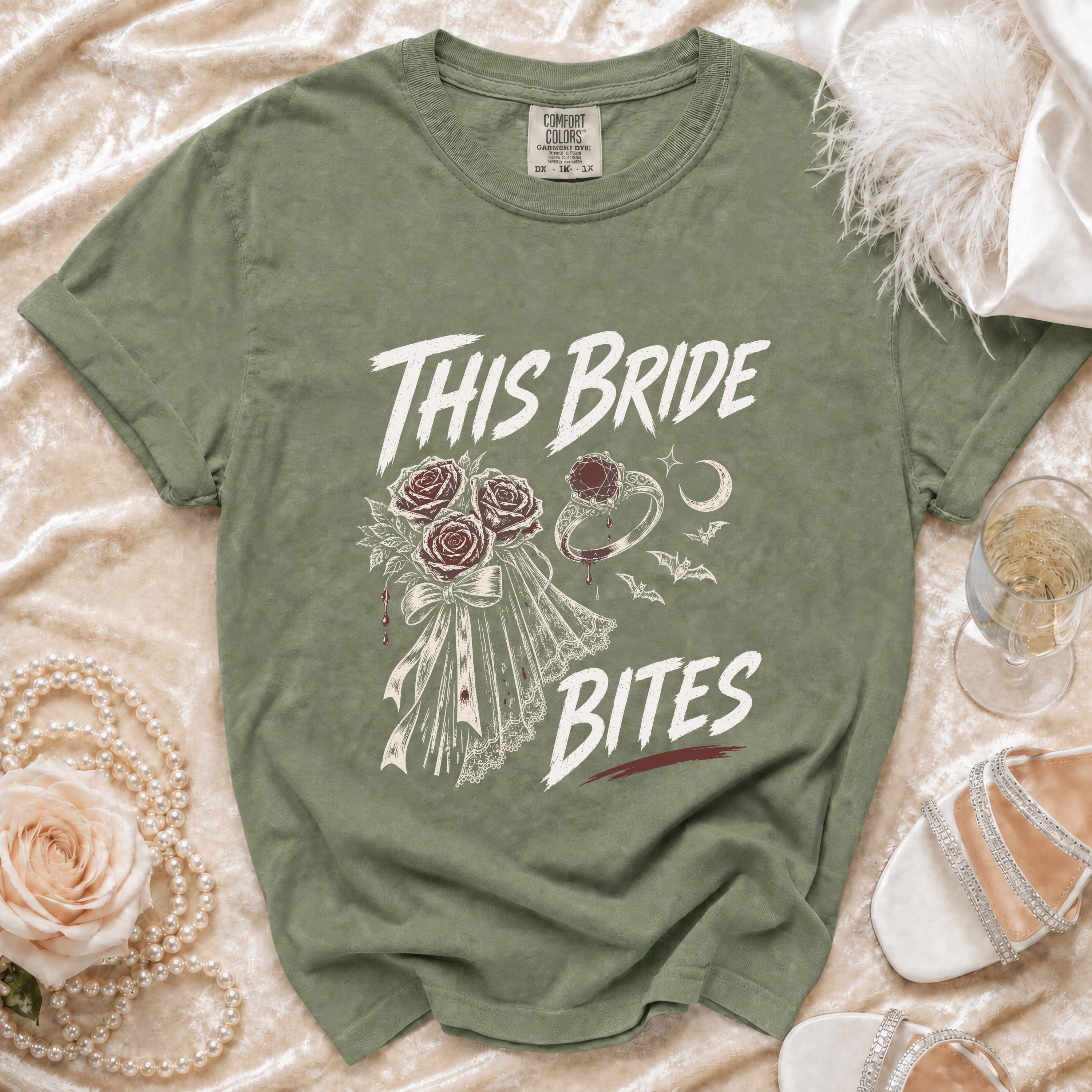 Olive green t-shirt with "This Bride Bites" text, bouquet, ring, and bats graphic.