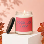 Lit candle in glass jar with pink label reading "GOOD LUCK, Babe. VOWED"