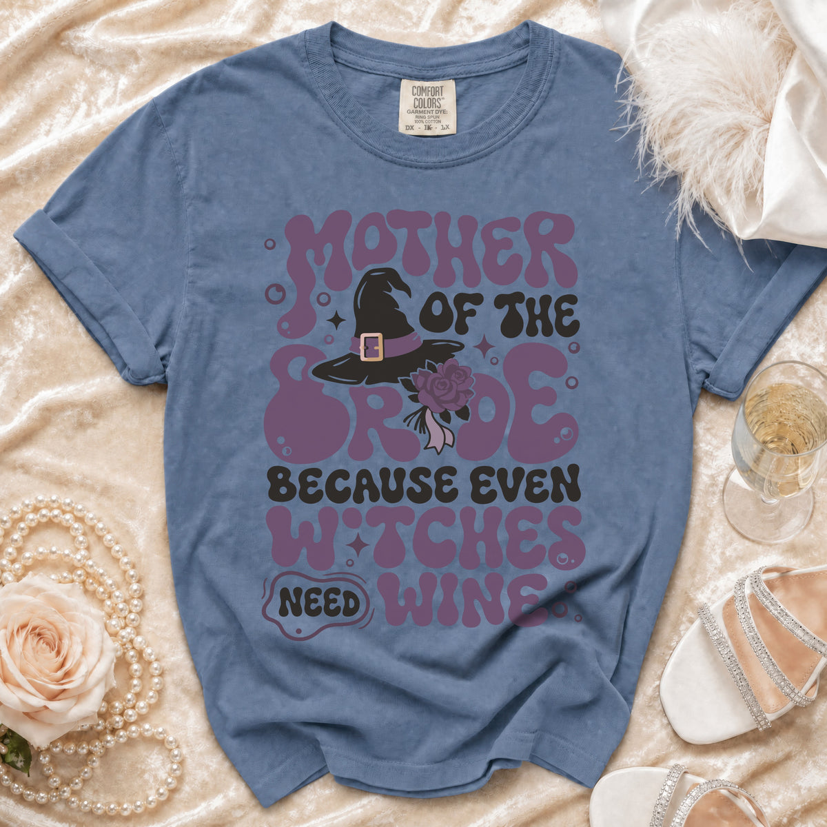 Blue t-shirt with "Mother of the Bride Because Even Witches Need Wine" text and witch hat graphic.