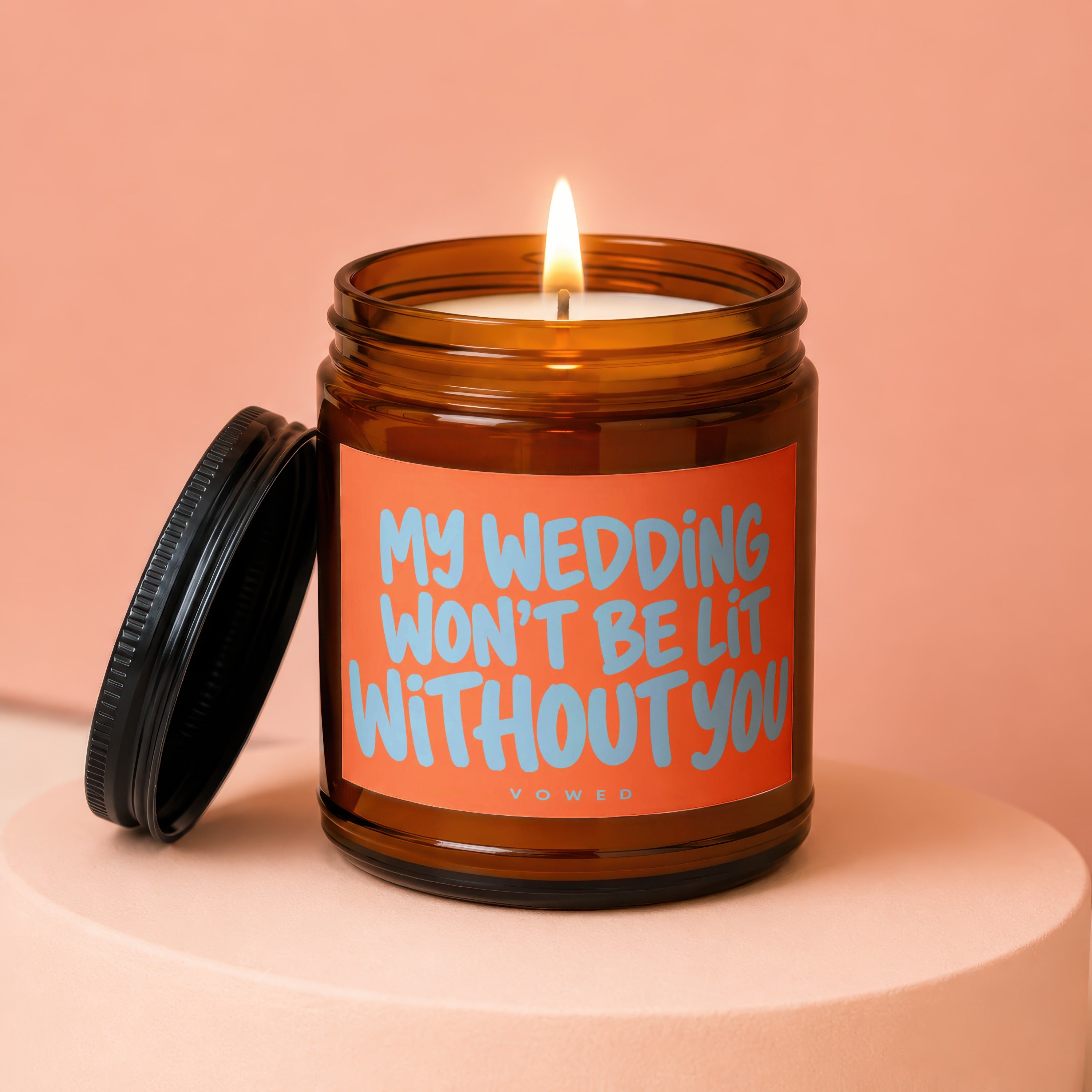 Candle with lit wick and orange label reading "MY WEDDING WON'T BE LIT WITHOUT YOU".