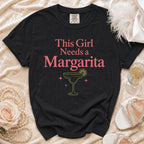 Black t-shirt with "This Girl Needs a Margarita" text and margarita graphic.