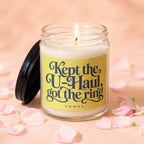 Candle with text "Kept the U-Haul, got the ring. VOWED" on yellow label, surrounded by petals.