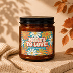 Amber candle with retro flower label reading "HERE'S TO LOVE! FROM YOUR BIGGEST FANS".