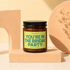 Brown jar candle with black lid, light green label saying "You're in the Bridal Party".