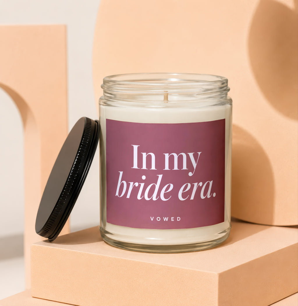 Glass jar candle with "In my bride era." and "VOWED" text on label.