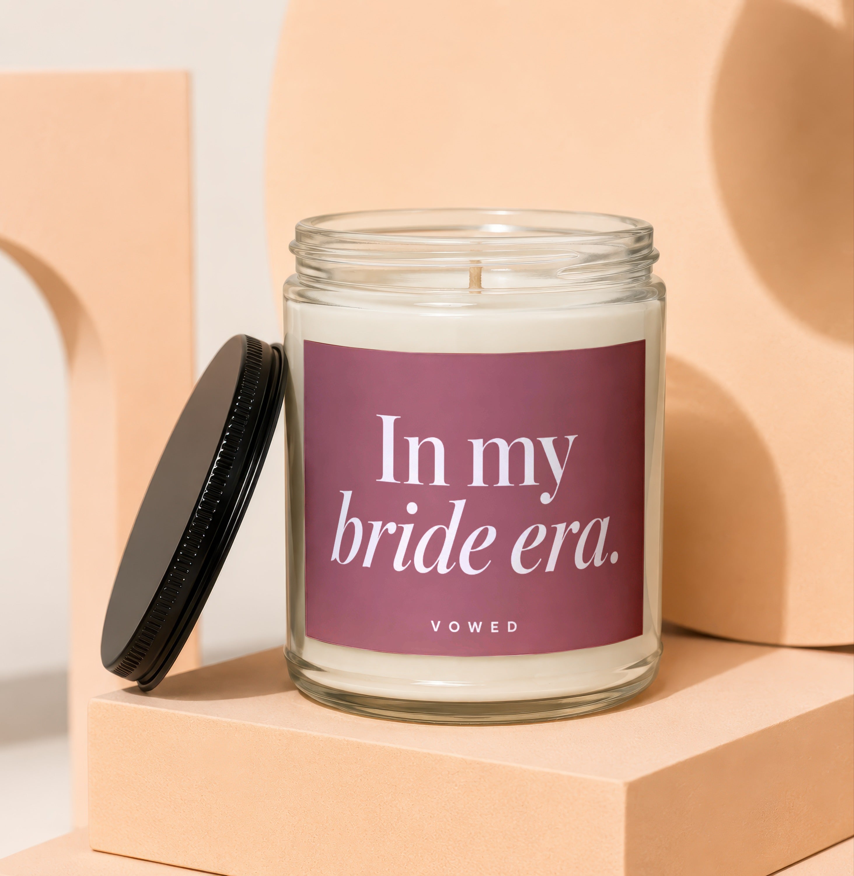 Glass jar candle with "In my bride era." and "VOWED" text on label.