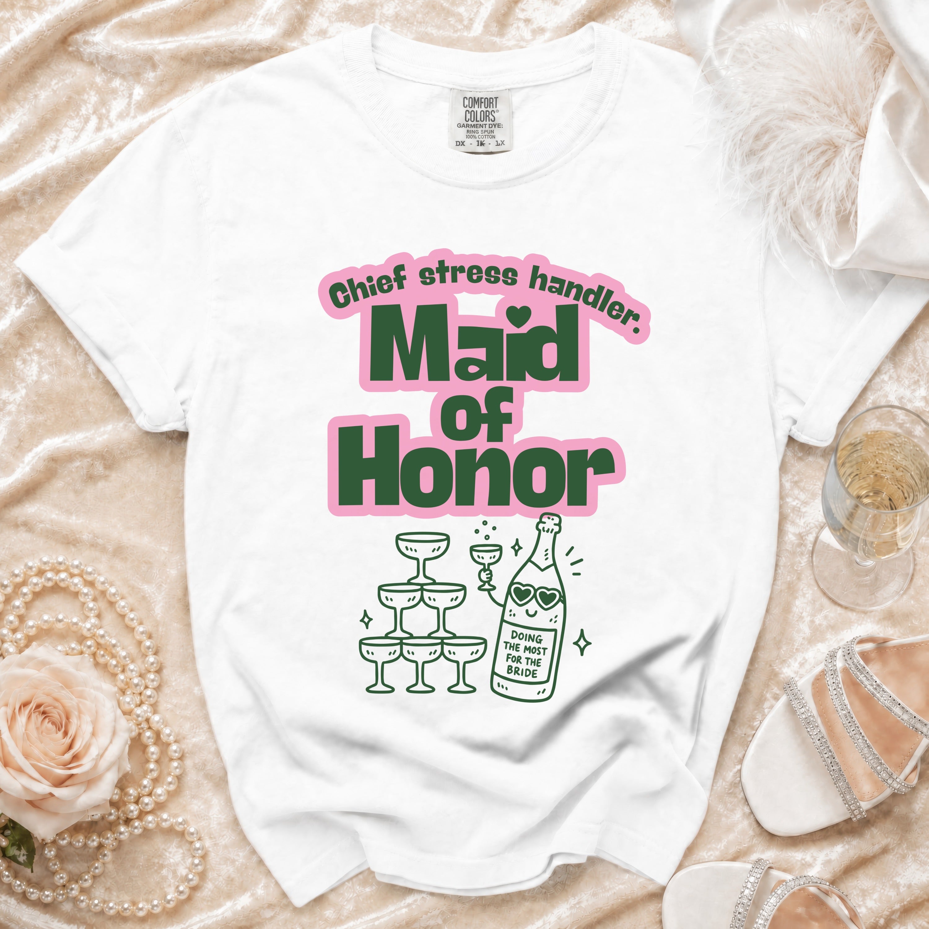 White t-shirt with "Maid of Honor" and "Chief stress handler" text and champagne illustration.