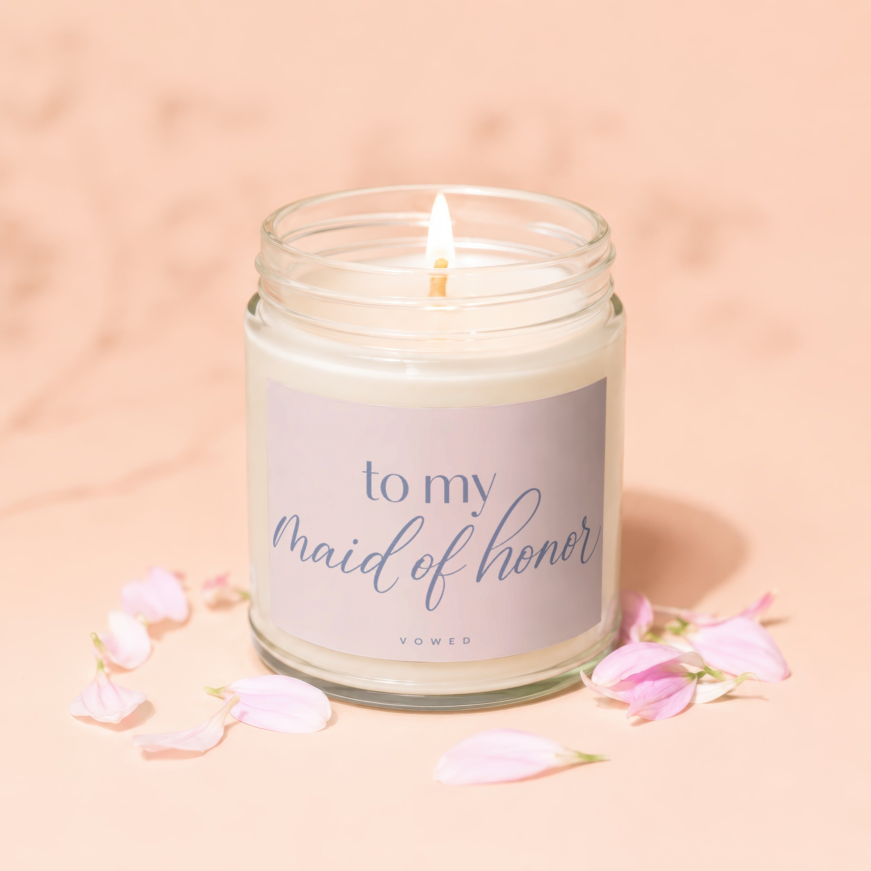 Lit candle in a glass jar with "To My Maid of Honor Vowed" text and pink petals.