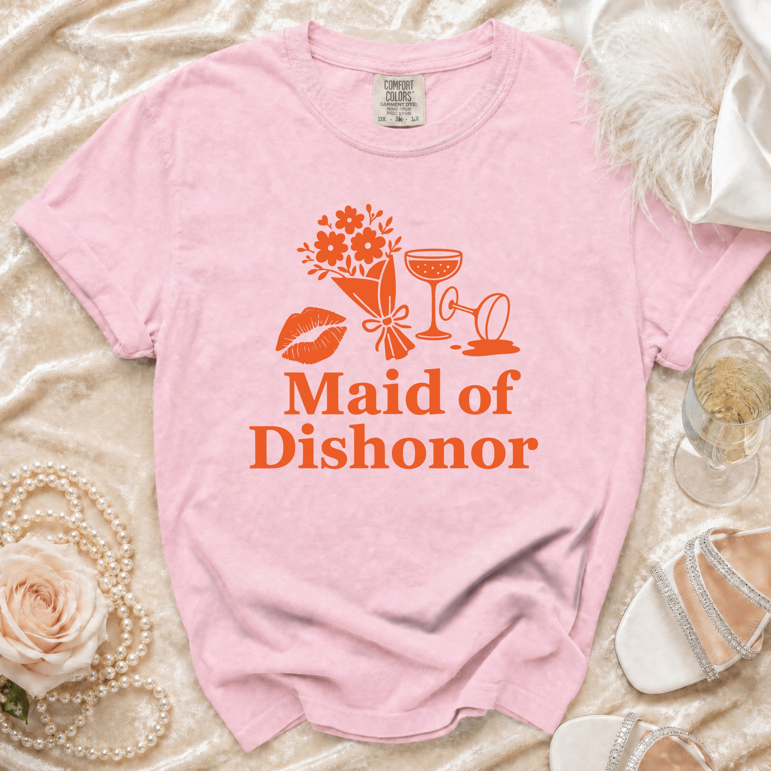 Pink t-shirt with orange graphic of lips, flowers, champagne glasses, and text Maid of Dishonor.