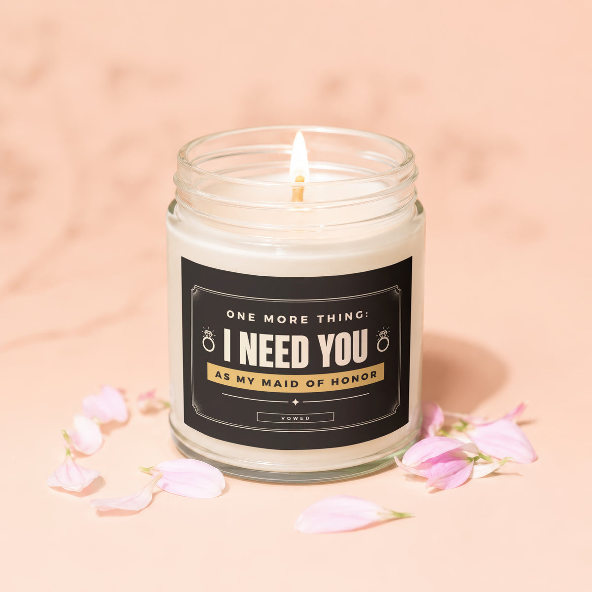 Glass candle with text "I NEED YOU AS MY MAID OF HONOR" surrounded by petals.