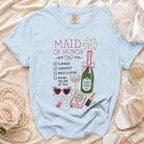 Light blue t-shirt with embroidered "MAID OF HONOR" checklist, champagne bottle, and accessories.