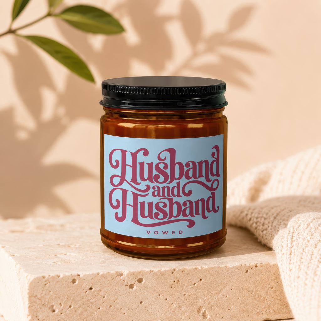 Candle with "Husband and Husband VOWED" in pink script on a light blue label.
