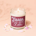 Glass jar candle with lit flame and label reading "Yaaas we said I do vowed".