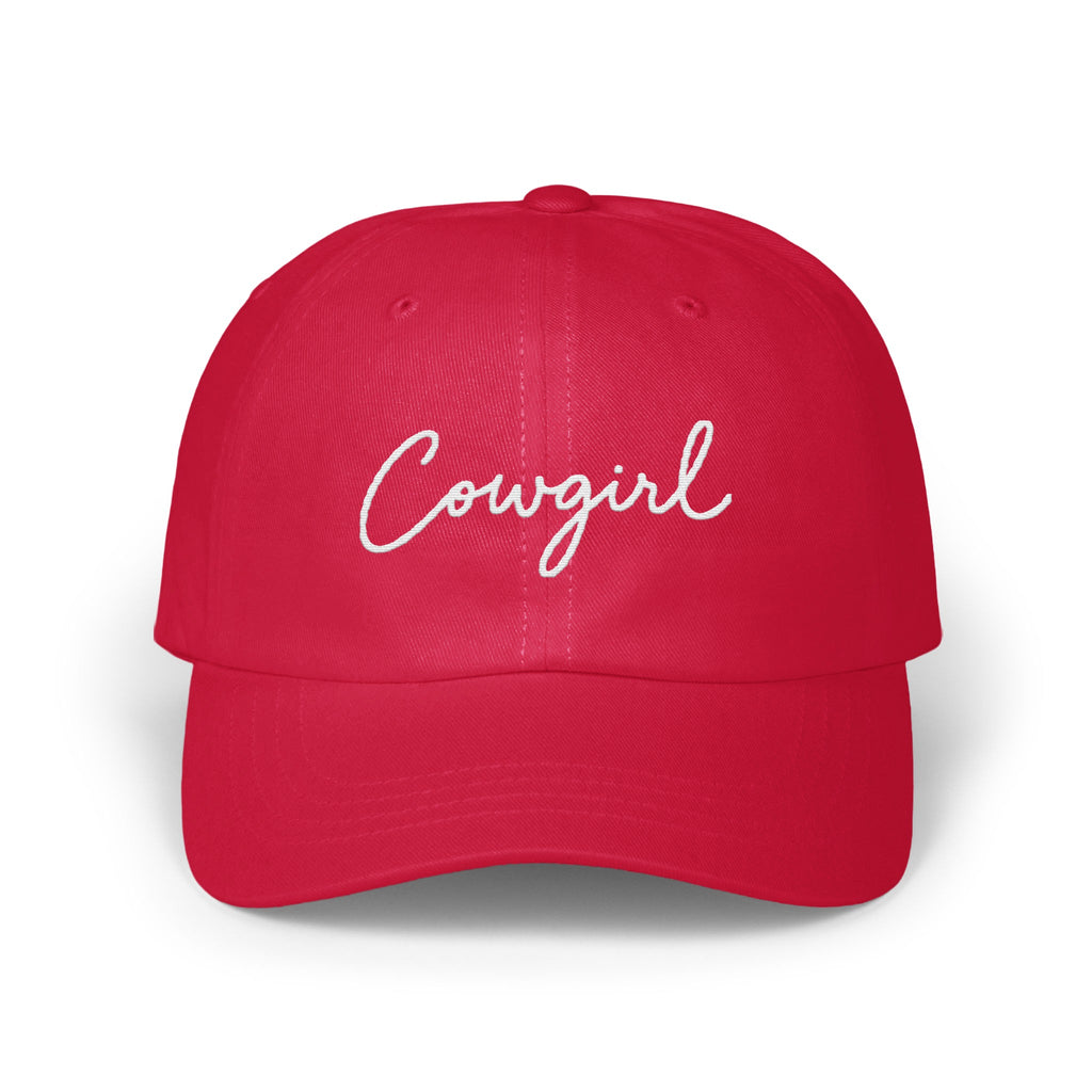 A red baseball cap embroidered with the word Cowgirl in white cursive lettering on the front.