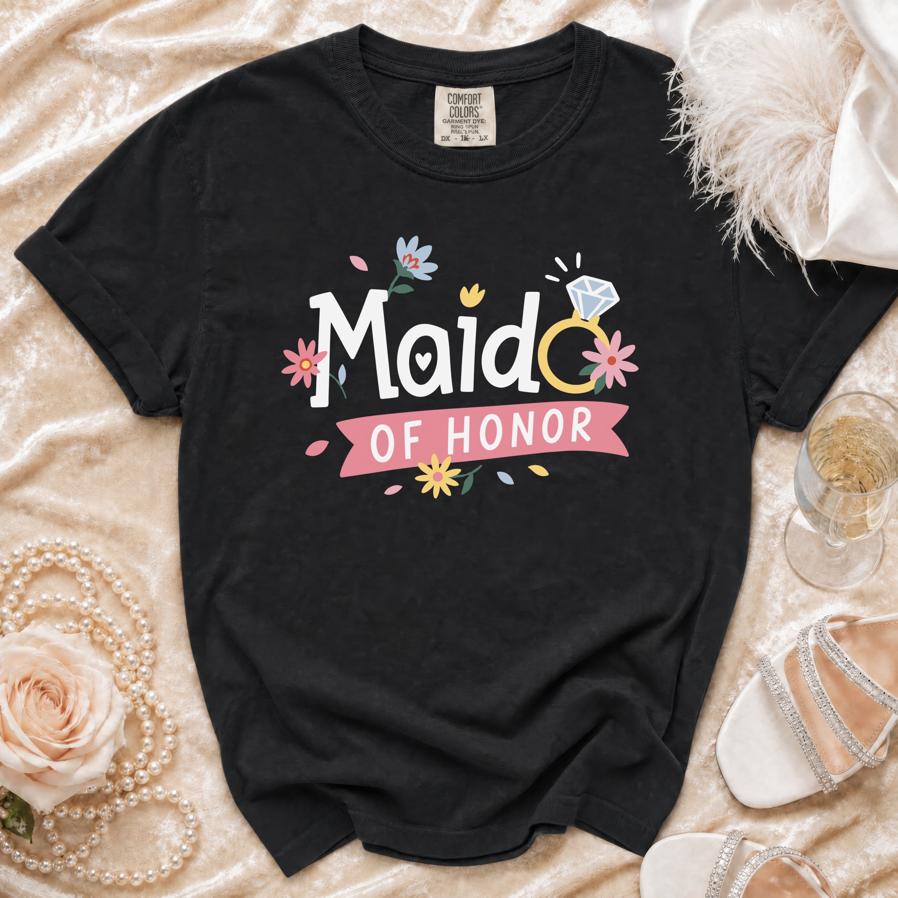 Black t-shirt with "Maid OF HONOR" printed in white with a diamond ring and floral accents.