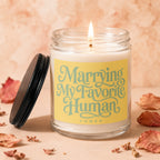 Lit candle in glass jar with "Marrying My Favorite Human" text; lid beside it.