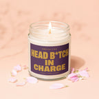 Candle with "Head B*tch In Charge" text, pink petals scattered around.
