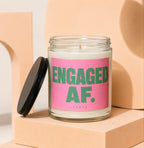 Glass jar candle with pink label reading "ENGAGED AF. VOWED".