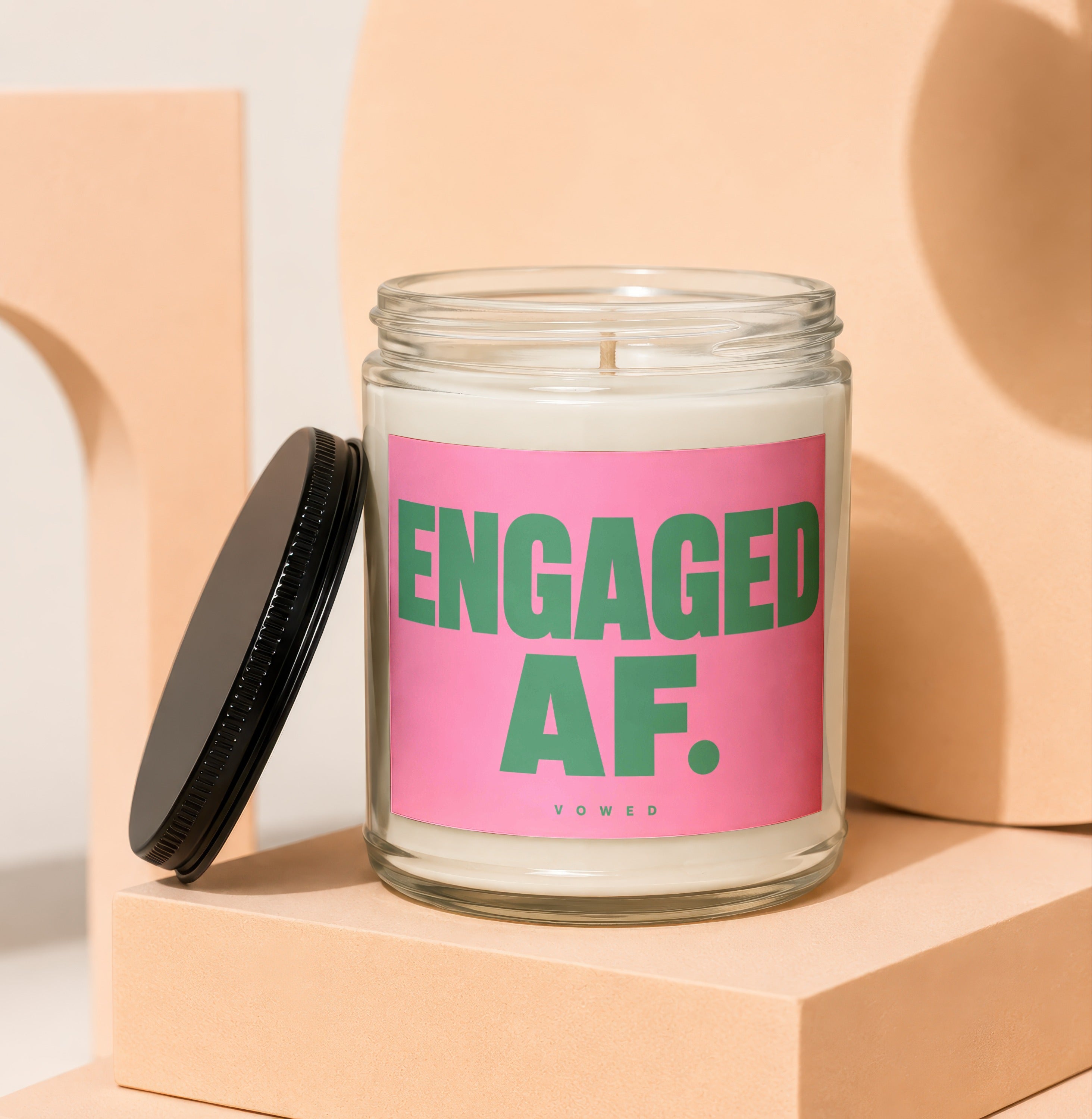 Glass jar candle with pink label reading "ENGAGED AF. VOWED".
