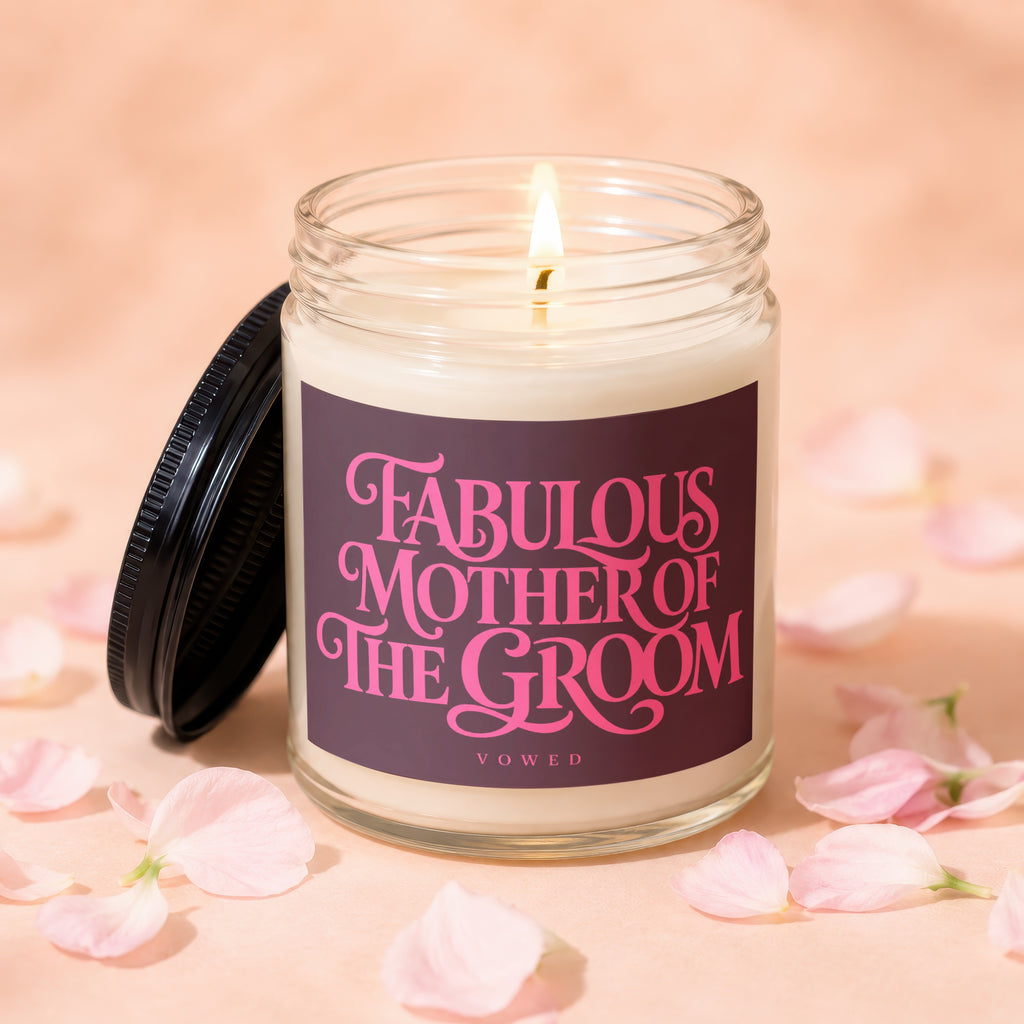 Glass candle with lit wick, inscribed "Fabulous Mother of the Groom", surrounded by pink petals.