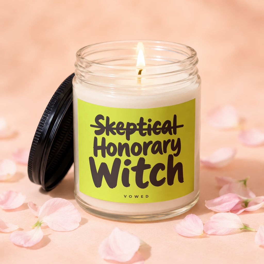 Glass candle with lid off, reads "Skeptical Honorary Witch Vowed".